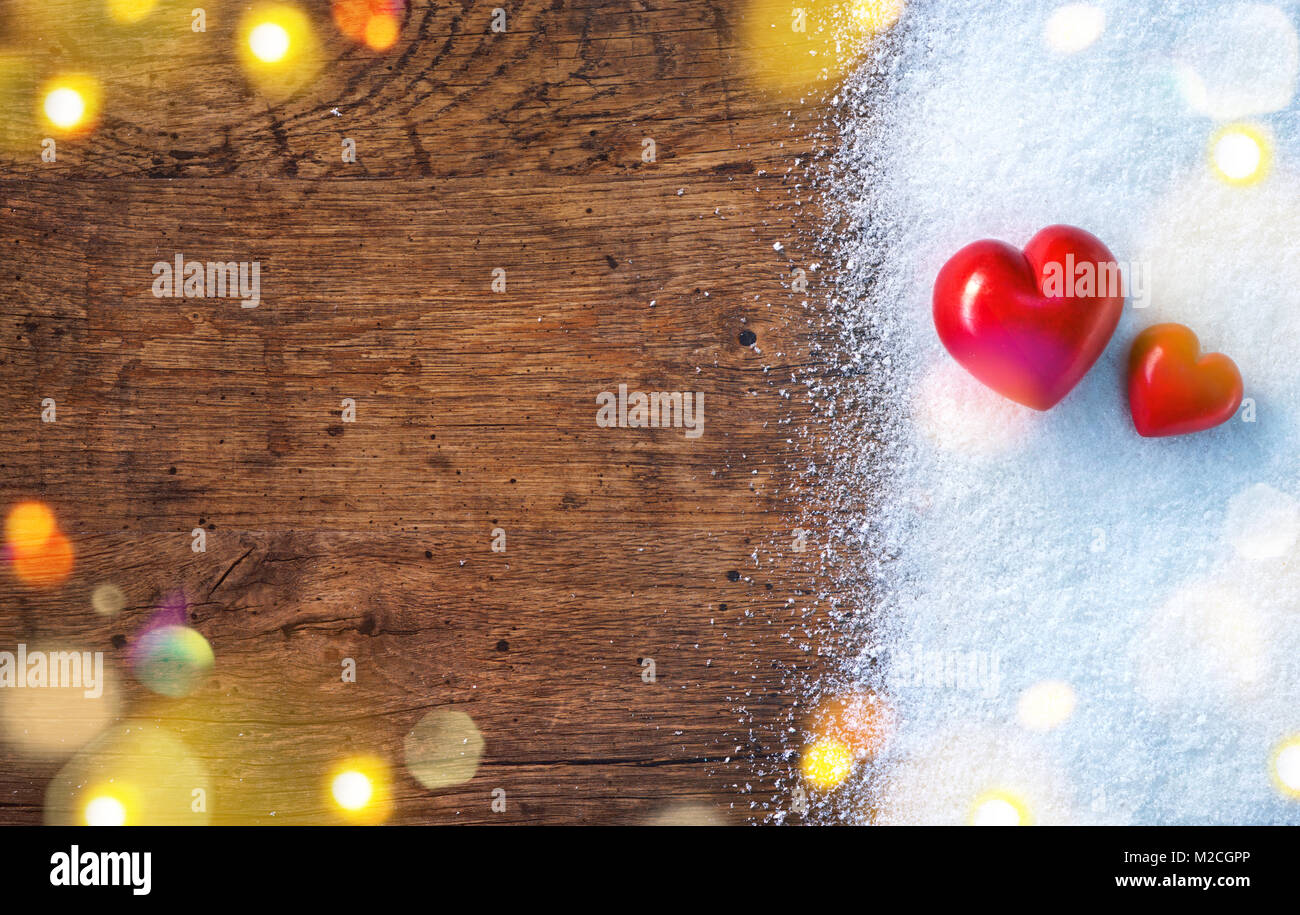 Due cuori rossi sulla neve e rustico sfondo. Amore e San Valentino concetto. Foto Stock