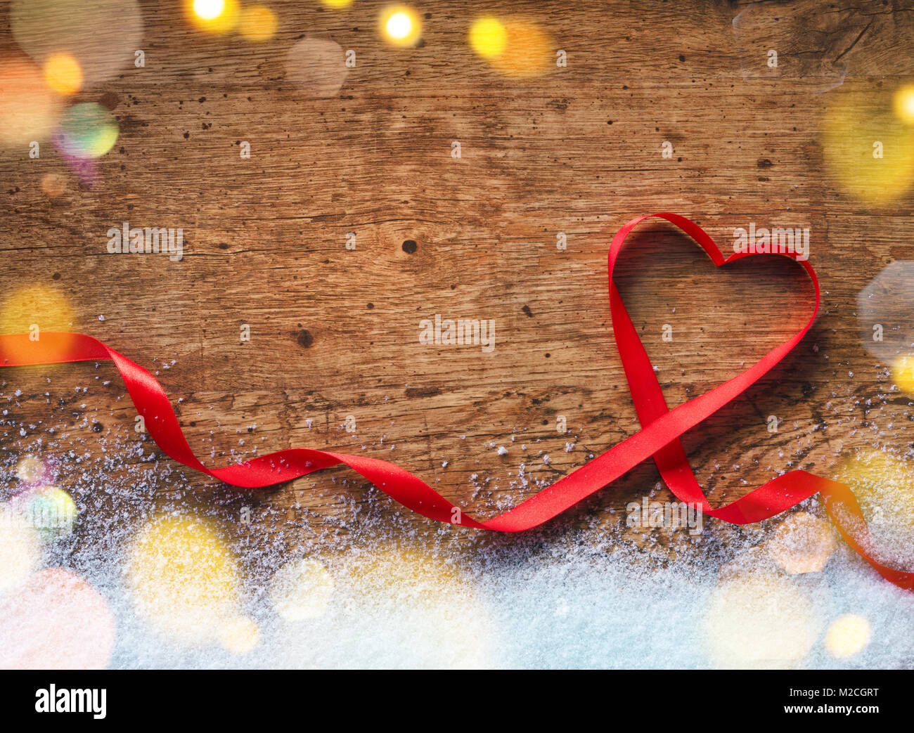 Felice il giorno di San Valentino. Nastro rosso cuore con neve su sfondo di legno. Vista superiore Foto Stock