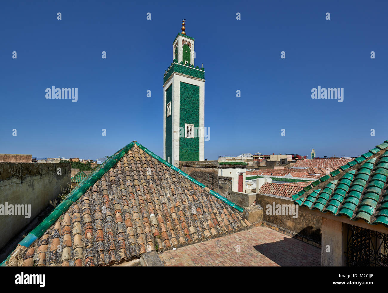Vista dal tetto del Bou Inania Madrasa con minareto della moschea e verde tetto islamica piastrelle, Meknes, Marocco, Africa Foto Stock