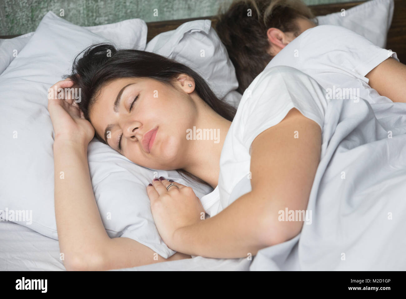 Bella giovane donna dormire comodamente nel letto confortevole con boyf Foto Stock