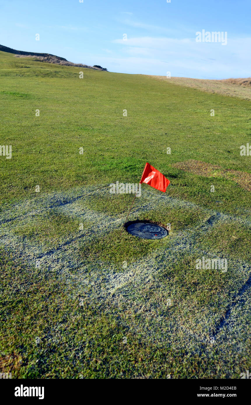 Indicatore rosso sul sito per il drenaggio e la cura del terreno di un campo da golf di colore verde durante il periodo invernale Foto Stock