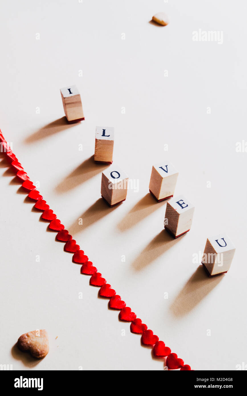 Lettera timbro formando la frase ' i love u' contro un pastello giallo sfondo per il giorno di san valentino giorno, vista dall'alto. Foto Stock