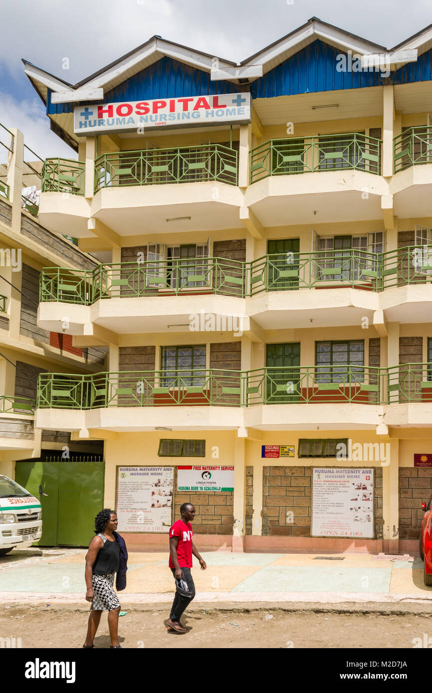 La parte esterna di un ospedale a Huruma con gente camminare passato su un polveroso sentiero di grandi dimensioni, Nairobi, Kenia Foto Stock
