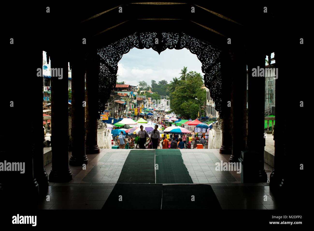 Uscita Shwedagon pagoda e di entrare in una trafficata strada frenetico mercato, riempite con colori ombrello si spegne. Colorato Yangon, birmania, myanmar, sud-est asiatico Foto Stock