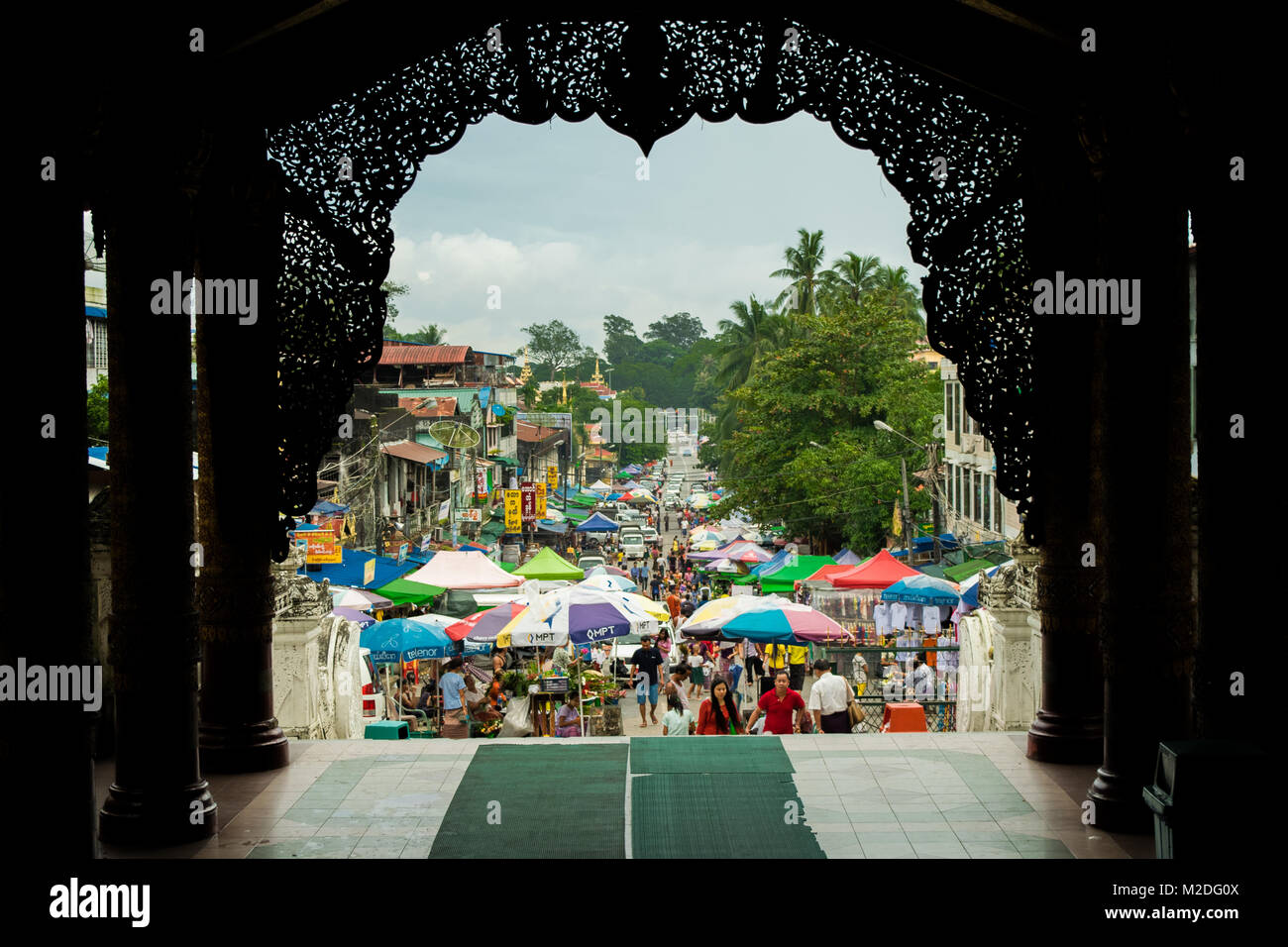 Uscita Shwedagon pagoda e di entrare in una trafficata strada frenetico mercato, riempite con colori ombrello si spegne. Colorato Yangon, birmania, myanmar, sud-est asiatico Foto Stock