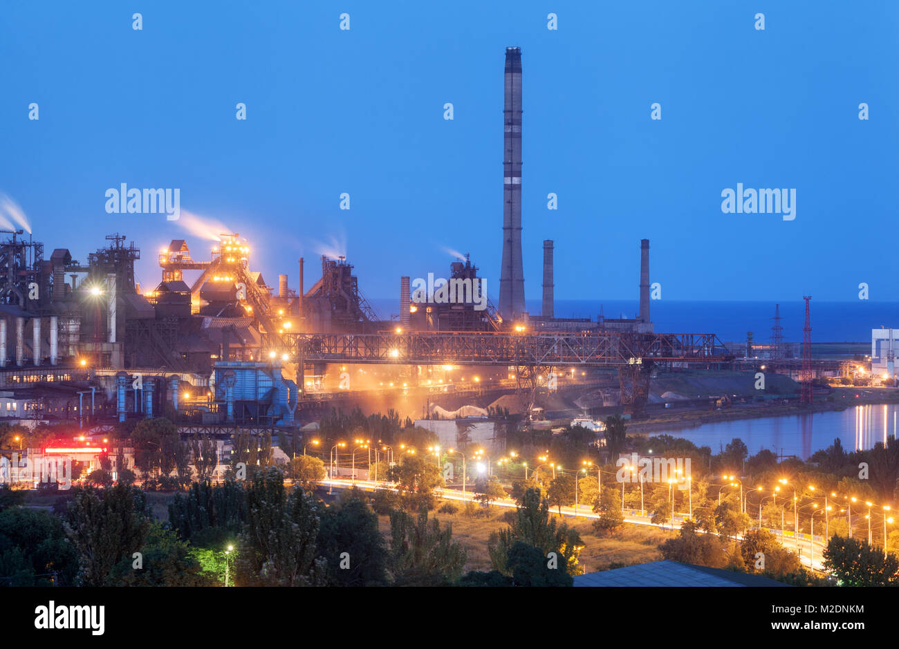 Stabilimento metallurgico di notte. Fabbrica di acciaio con fumaioli. Acciaierie e lavori di ferro. Industria pesante in Europa. Inquinamento atmosferico da fumaioli ecolog Foto Stock