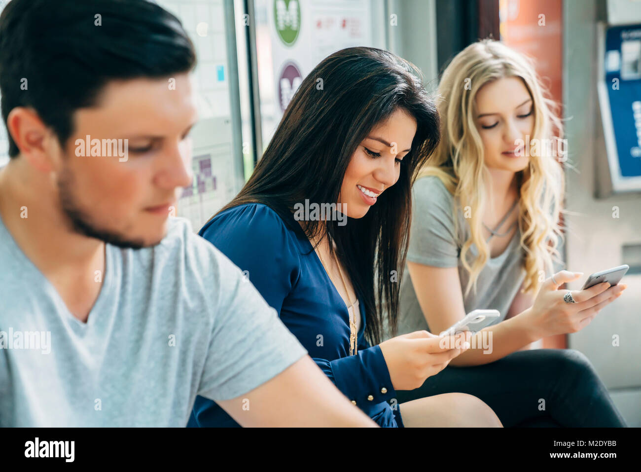 Le donne scrivere messaggi su telefoni cellulari alla stazione ferroviaria Foto Stock