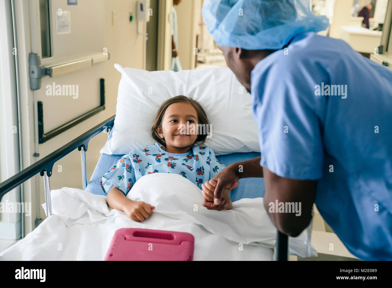 Medico tenendo la mano della ragazza nel letto di ospedale Foto Stock
