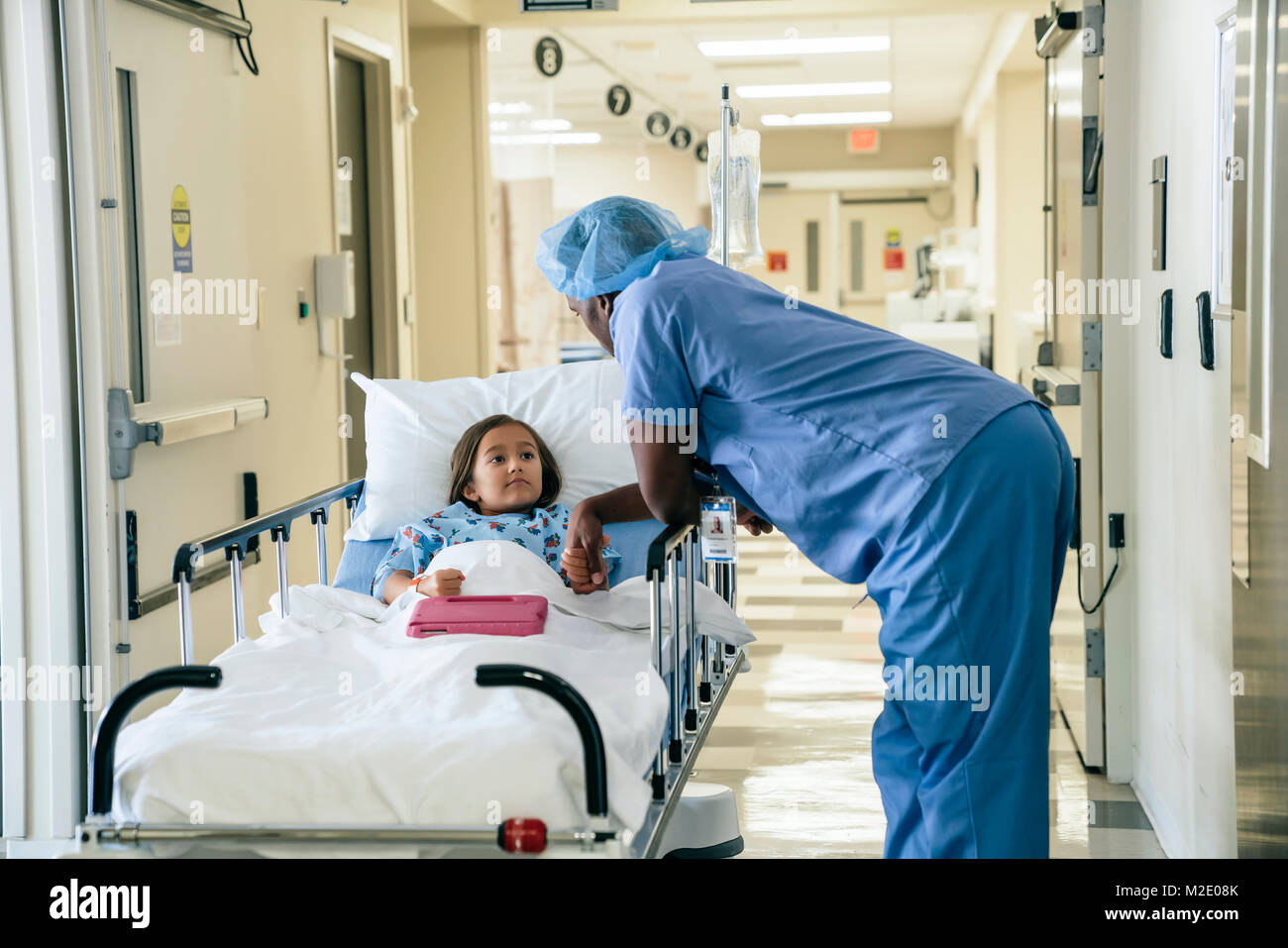 Medico tenendo la mano della ragazza in ospedale gurney Foto Stock