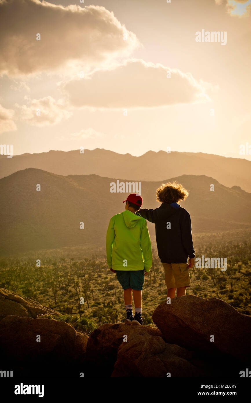 Ragazzi in piedi sulla roccia ammirando il paesaggio del deserto Foto Stock