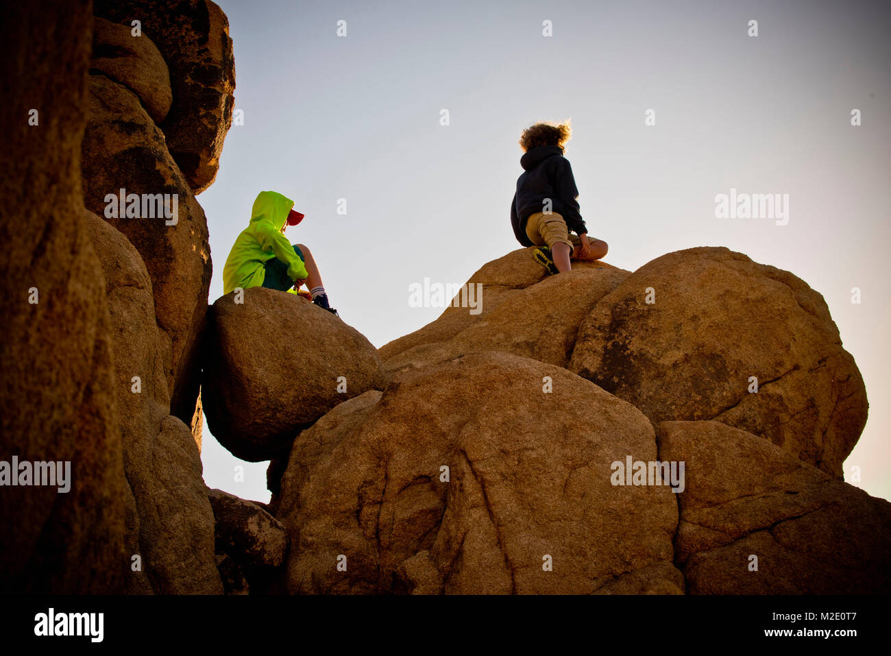 Ragazzi seduti sulle rocce sotto il cielo blu Foto Stock