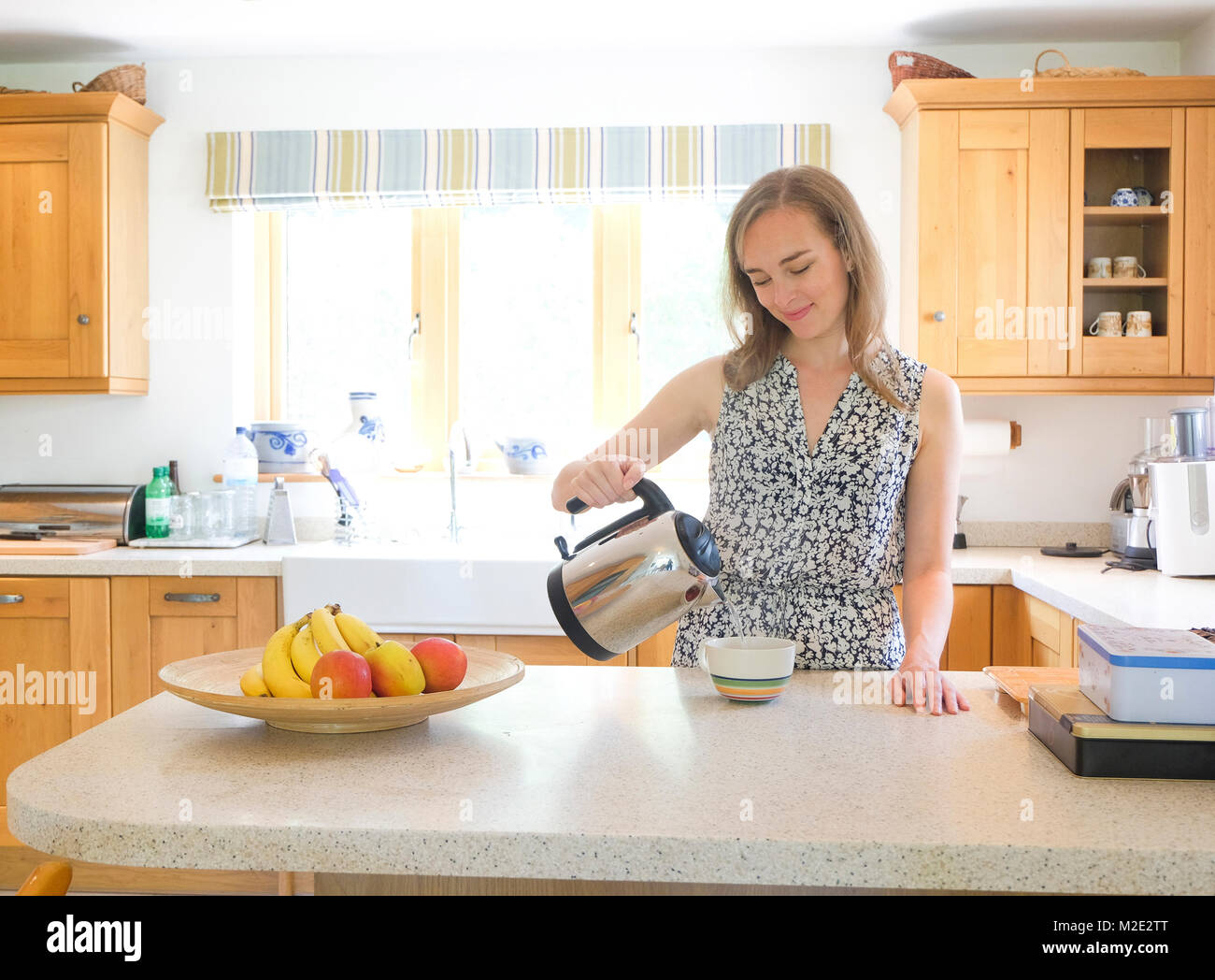 La donna caucasica analizzato il caffè dalla pentola in cucina Foto Stock