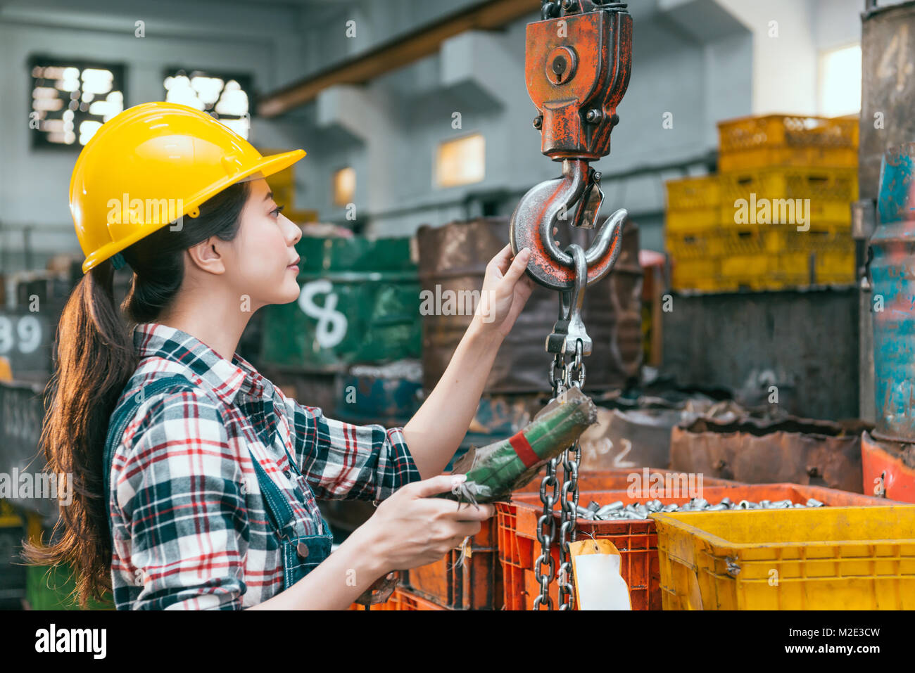 Giovane e bella macchina fresatrice factory lavoratore di sesso femminile che la regolazione della catena di lavorazione gru la preparazione di Tornio per la spedizione di prodotti finiti. Foto Stock