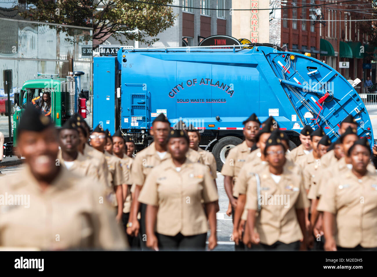 Alta scuola junior ROTC cadetti marzo in Georgia i veterani parata del giorno, come una città di Atlanta igiene blocchi del carrello su un lato della strada di Atlanta, GA. Foto Stock
