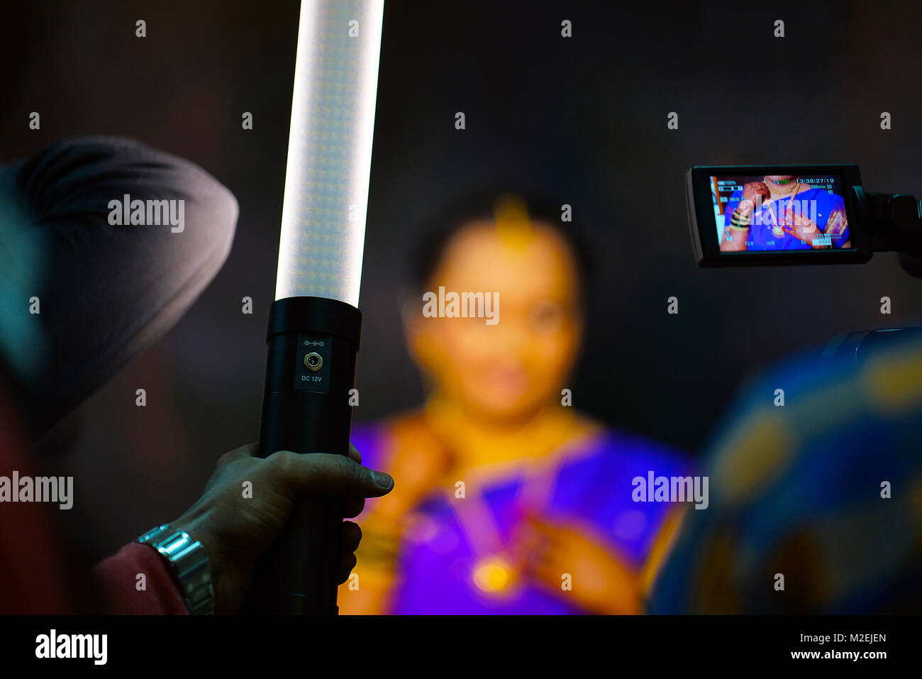 Il fotografo è strumento di una macchia di luce portatile utilizzato per illuminato solo il viso della persona soggetta in photo frame. Il videografo ha una telecamera fissa sulla sposa Foto Stock