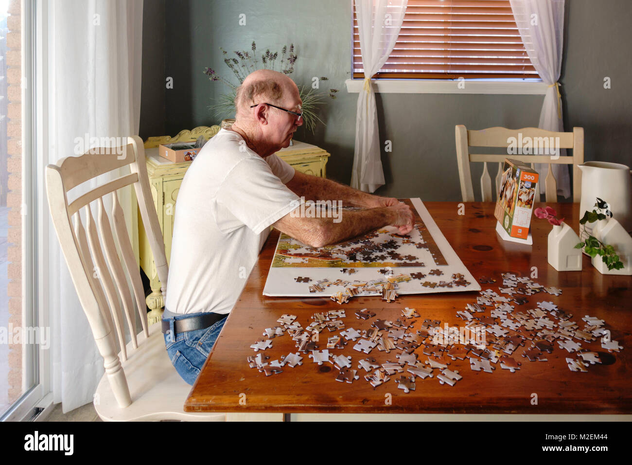 Un anziano, o uomo anziano con demenza funziona un puzzle di affinare la sua capacità mentali. Oklahoma, Stati Uniti d'America. Foto Stock