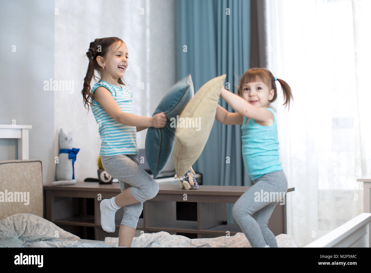 I ragazzi ragazze divertirsi giocando con cuscini in camera da letto a casa Foto Stock