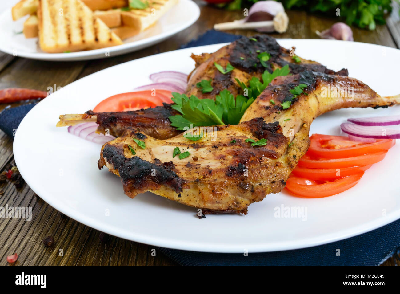 Coniglio fritto gambe su una piastra bianca su di un tavolo di legno. Dieta  a base di carne di coniglio cotto alla griglia Foto stock - Alamy