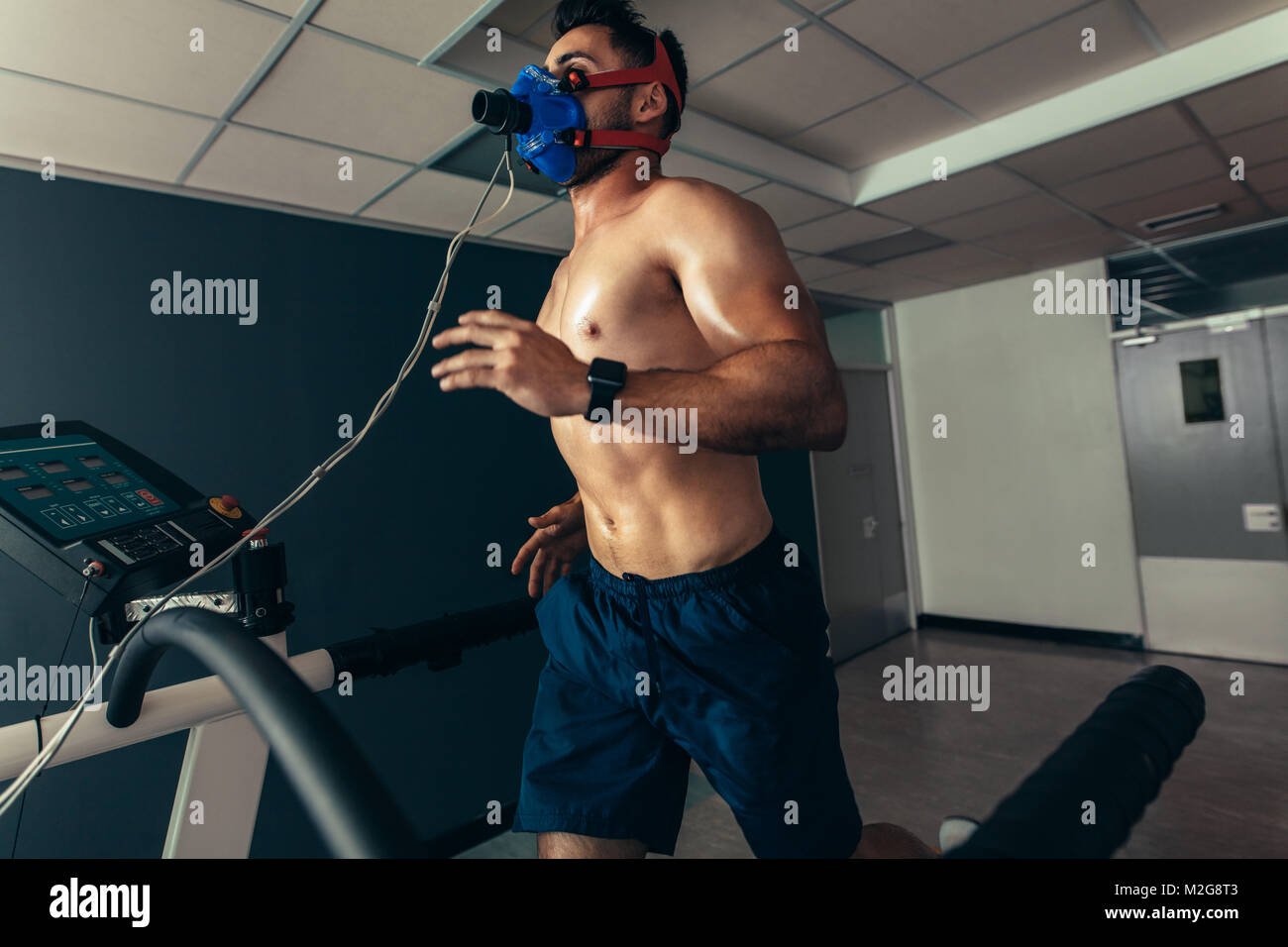Atleta facendo una prova delle prestazioni sportive in laboratorio. Runner con maschera in esecuzione sulla macchina tapis roulant e test delle prestazioni. Foto Stock