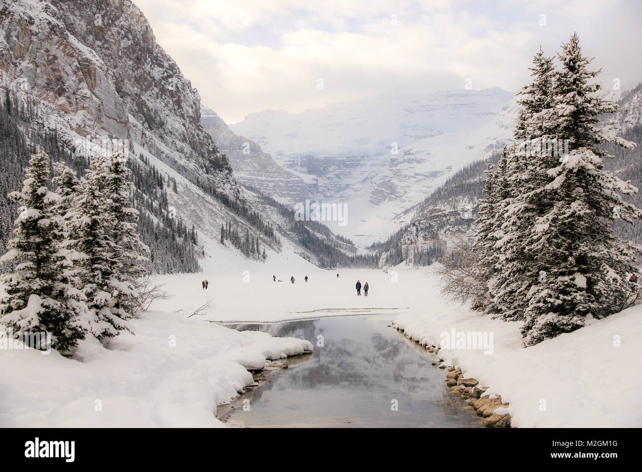 Lago ghiacciato di Louise nel Parco Nazionale di Banff, coperto di neve. Alcuni escursionisti su di esso. Il Canada in inverno. Foto Stock