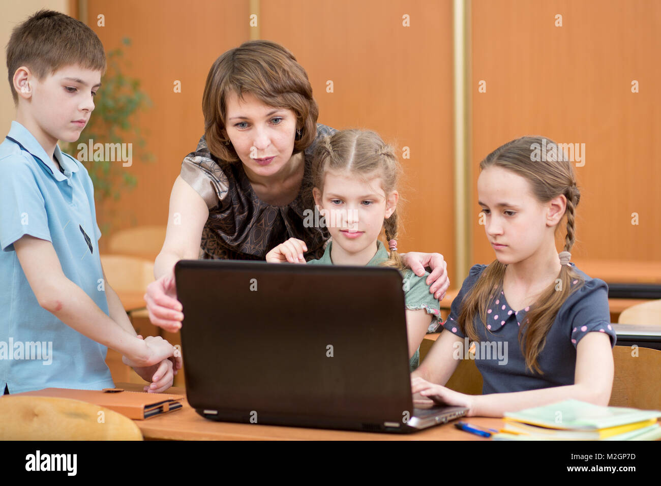 I bambini della Scuola e insegnante al computer portatile in aula Foto Stock