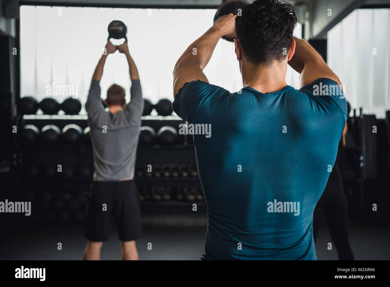 Uomo e donna in palestra a lavorare insieme in un gruppo o un team kettlebells di sollevamento. Foto Stock