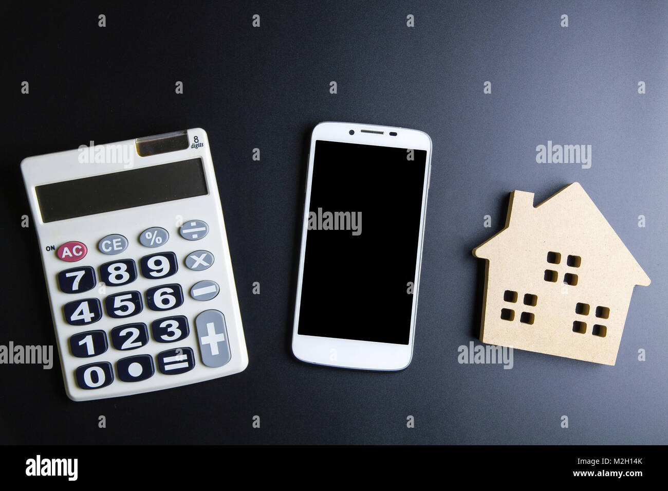 Casa in legno giocattolo, Calcolatrice e Smartphone su sfondo nero con spazio copia.immobiliare di concetto, casa nuova nozione, finanza prestito il concetto di business, Foto Stock