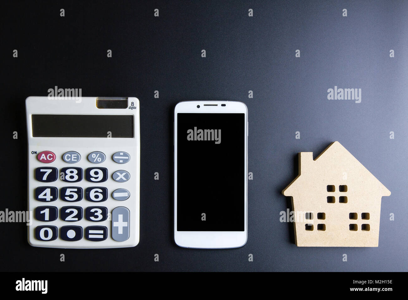 Casa in legno giocattolo, Calcolatrice e Smartphone su sfondo nero con spazio copia.immobiliare di concetto, casa nuova nozione, finanza prestito il concetto di business, Foto Stock