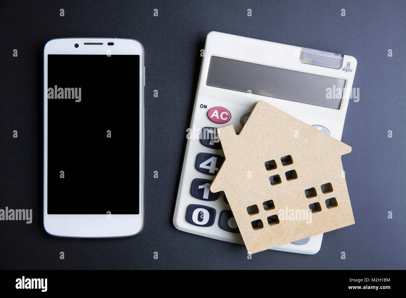 Casa in legno giocattolo, Calcolatrice e Smartphone su sfondo nero con spazio copia.immobiliare di concetto, casa nuova nozione, finanza prestito il concetto di business, Foto Stock