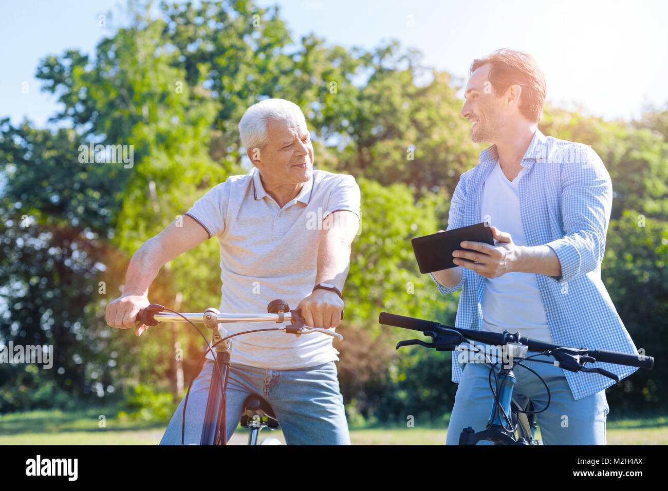 Padre e figlio utilizzando il touchpad mentre cavalcate le loro biciclette Foto Stock