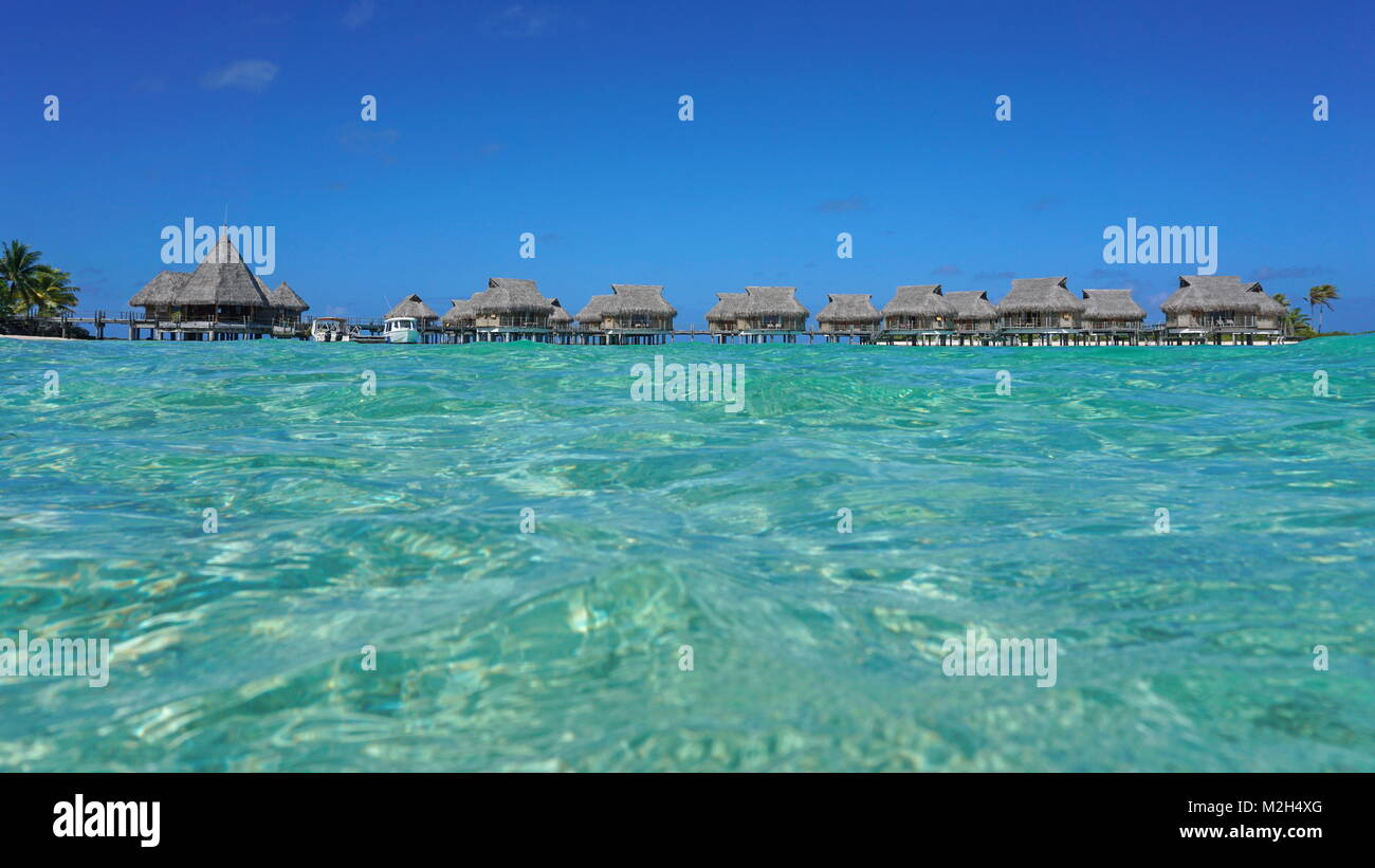 Resort tropicale con bungalow con tetto in paglia in laguna visto dalla superficie del mare, Tikehau Atoll, Tuamotus, Polinesia francese, oceano pacifico, Oceania Foto Stock