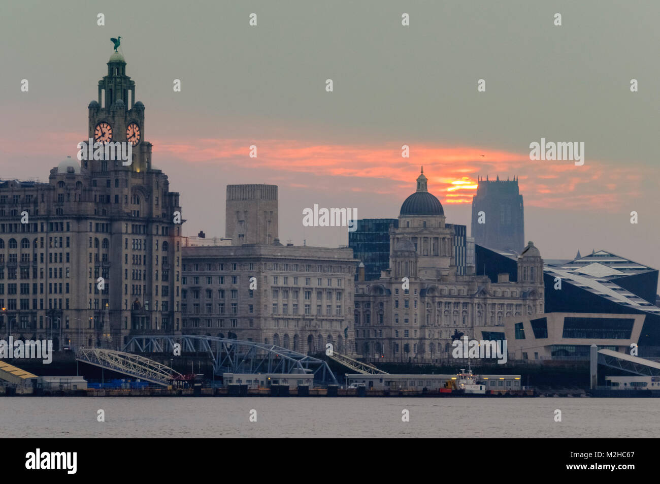 Il Liverpool Cattedrale Anglicana di distanza con un inizio di mattina orange il sorgere del sole sopra il Liverpool waterfront. Foto Stock