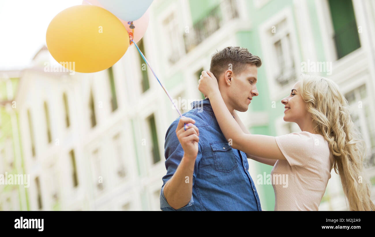 Ragazza bionda abbracciando amata giovane uomo, giovane dating, tenendo palloncini, stock video Foto Stock