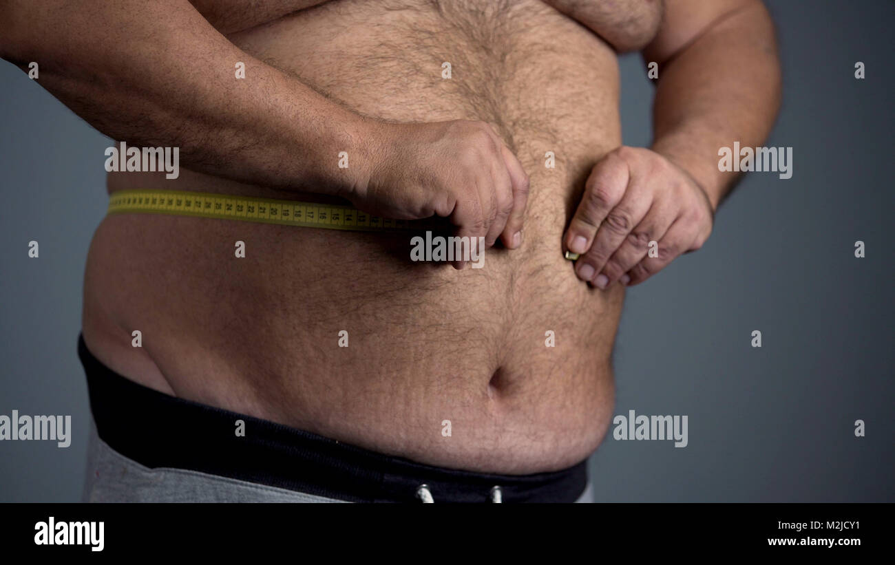 Triste Uomo sovrappeso in grado di misurare la sua vita, grasso pancia con  smagliature, stock footage Foto stock - Alamy