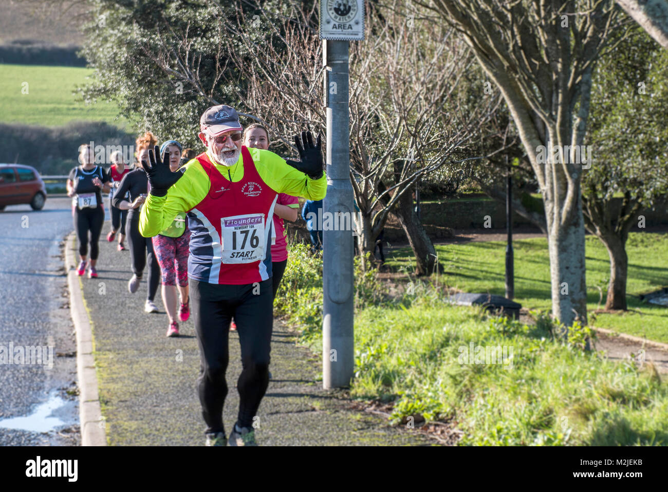 Un maschio maturo runner leader di un gruppo di corridori per competere in una gara su strada in Newquay Cornwall. Foto Stock