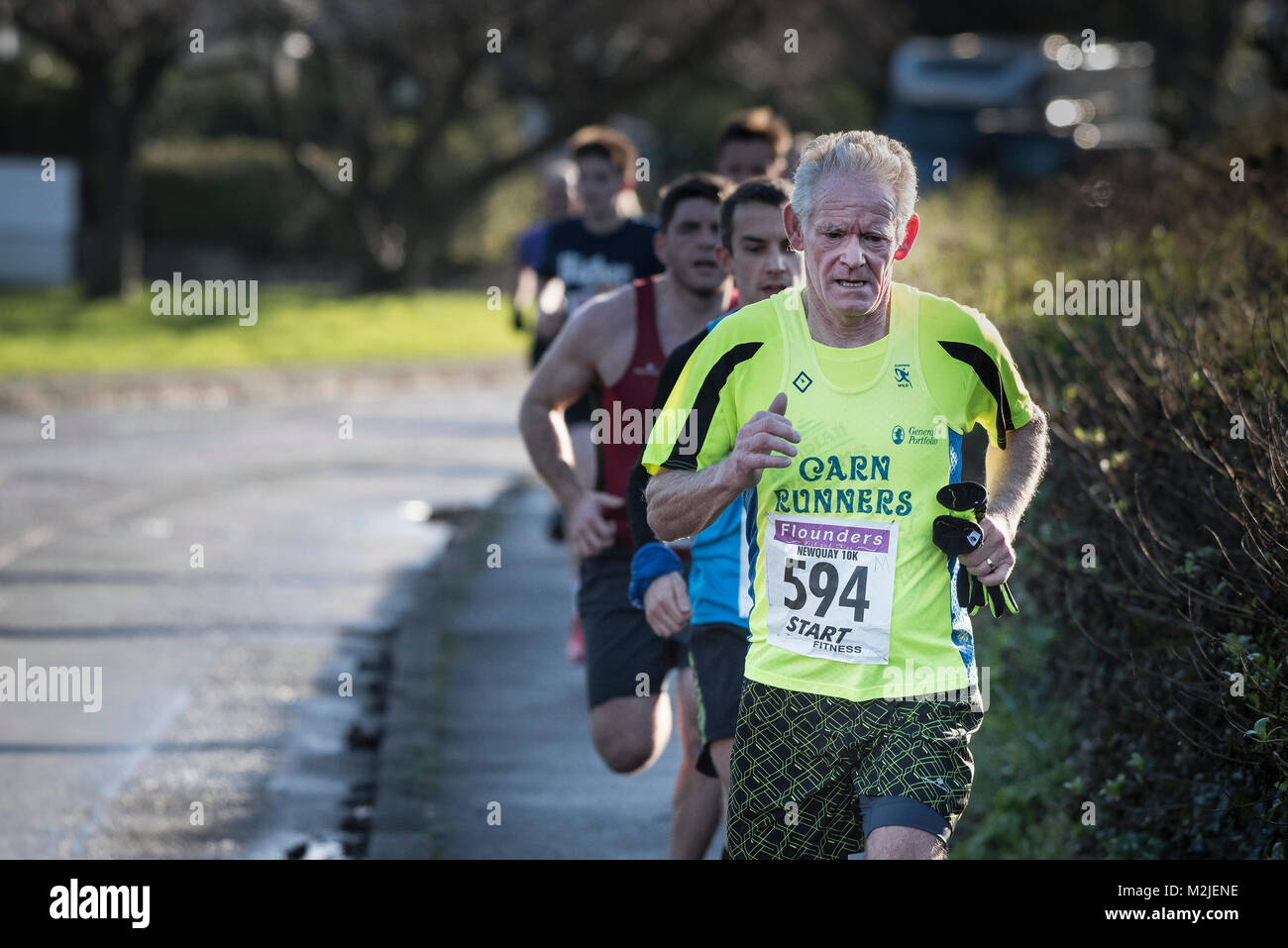 Una matura runner leader di un gruppo di corridori per competere in una gara su strada in Newquay Cornwall. Foto Stock