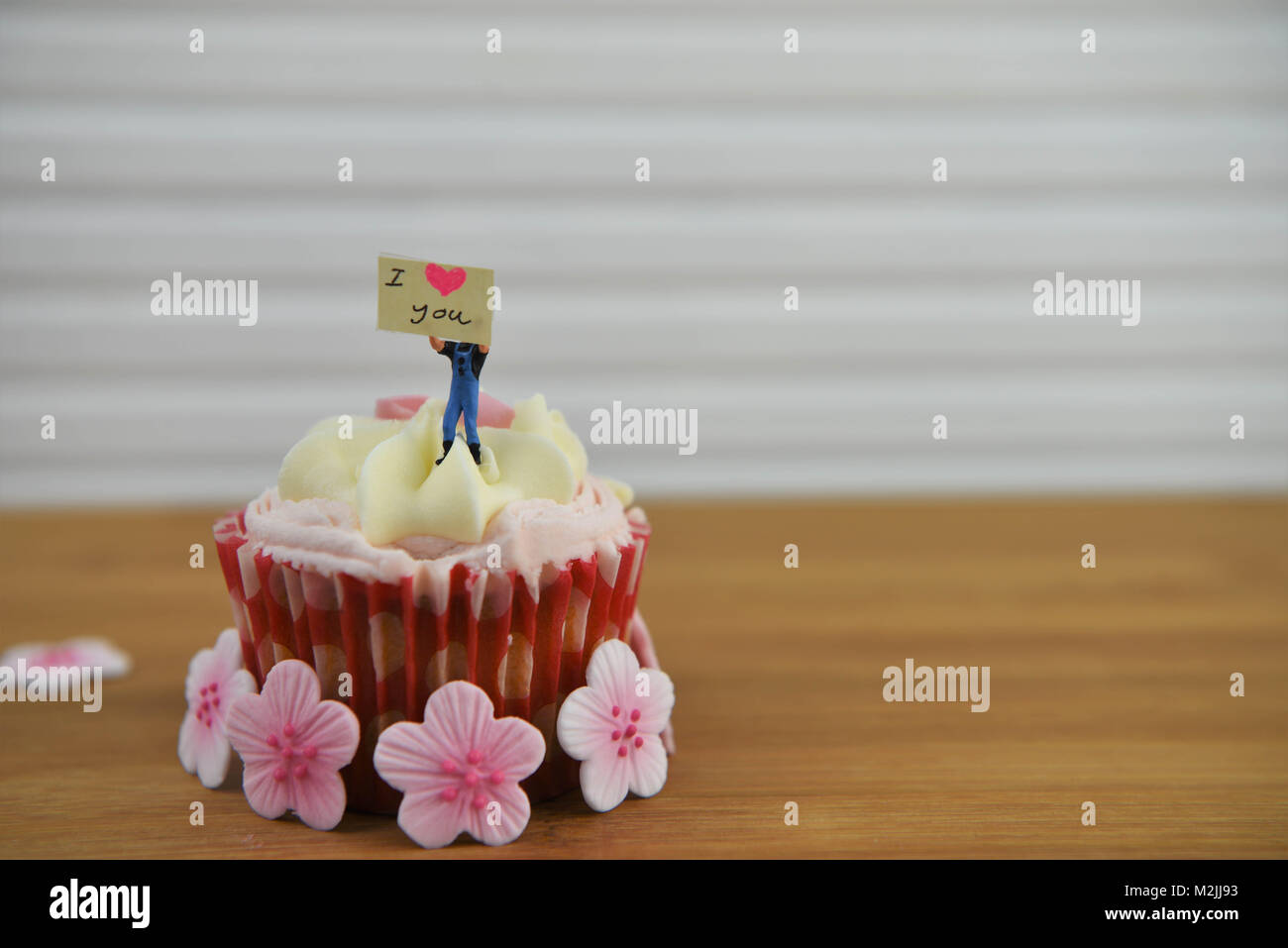 Romantico San Valentino cupcake decorato con una persona in miniatura figurina tenendo un cartello e amore forma di cuore Foto Stock