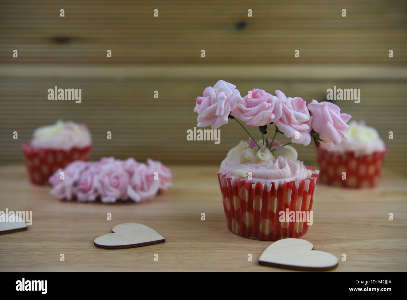 Romantica coppa artigianali torte con rosa e bianco ghiaccio e riccioli di cioccolato con rosa miniatura carta rose e amore forme di cuore Foto Stock