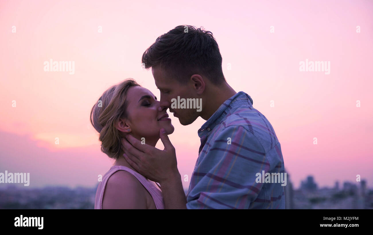 Amare giovane appassionatamente kissing, meeting Alba sul tetto di un edificio alto Foto Stock