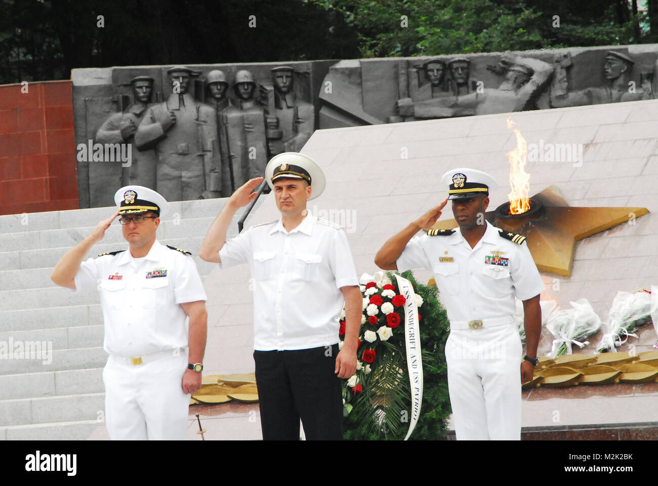 100724-N-4894D-311 VLADIVOSTOK, RUSSIA (24 luglio 2010) della Cmdr. Steven Prescott, sinistra, comandante della guidato-missile fregata USS Vandegrift (FFG 48), Lt. La Cmdr. Walter Mainor, destra, comandante della miniera contromisure nave USS Patriot (MCM 7), e una marina russa della Cmdr. Rendere onori durante una ghirlanda di cerimonia di posa a Vladivostok. Vandegrift e Patriot sono una visita in Russia a partecipare a Navy alle celebrazioni del Giorno a Vladivostok. (U.S. Navy foto di Lt. Colby Drake/RILASCIATO) Russo e American marinai alla cerimonia da EUCOM Foto Stock