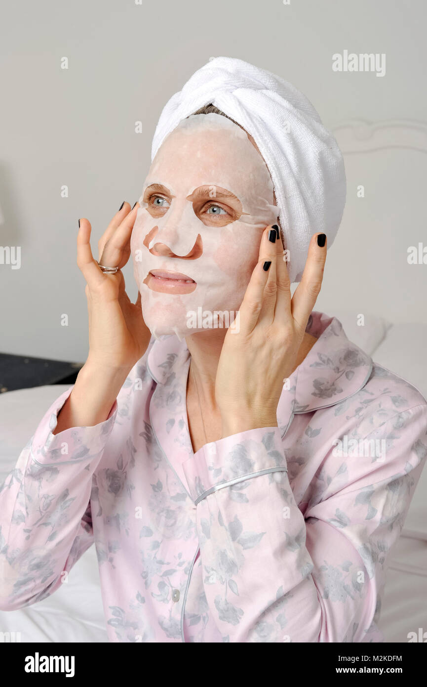 La donna nella sua camera da letto utilizzando trattamenti di bellezza Prima dorme. Foto Stock