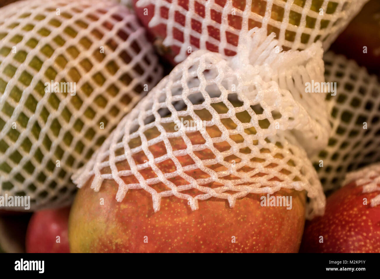 Pila di red manghi nel loro involucri protettivi, still-life Foto Stock