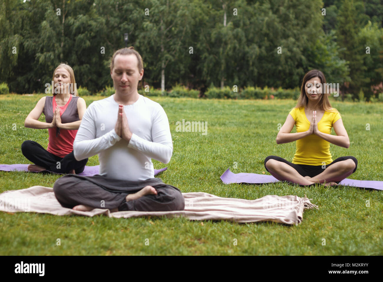 Lo Yoga sportivi nel parco - gli atleti in lotus pongono Foto Stock