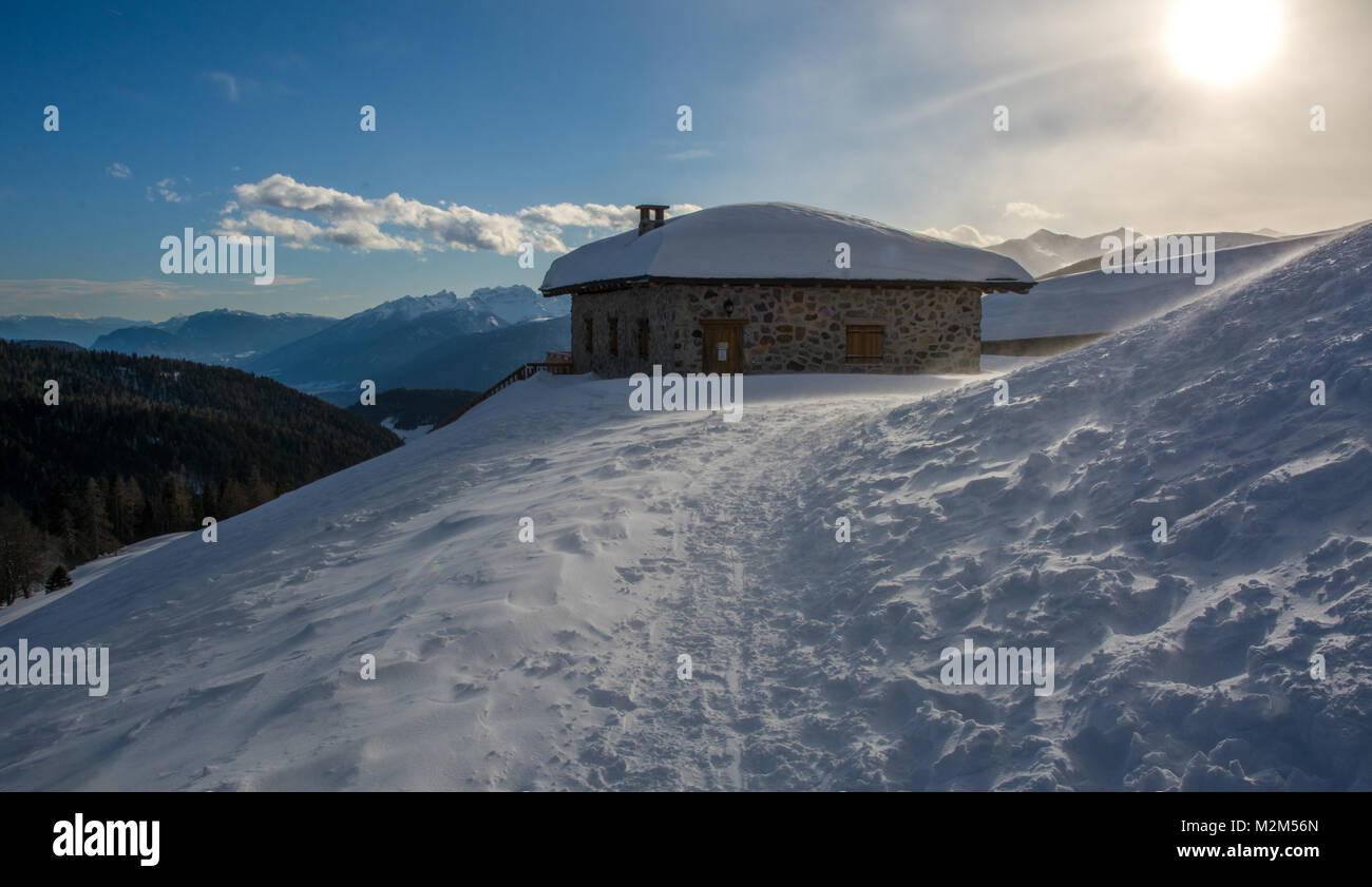 Vista panoramica di idilliaci winter wonderland con cime e tradizionali chalet di montagna nelle Dolomiti nella luce del tramonto Foto Stock