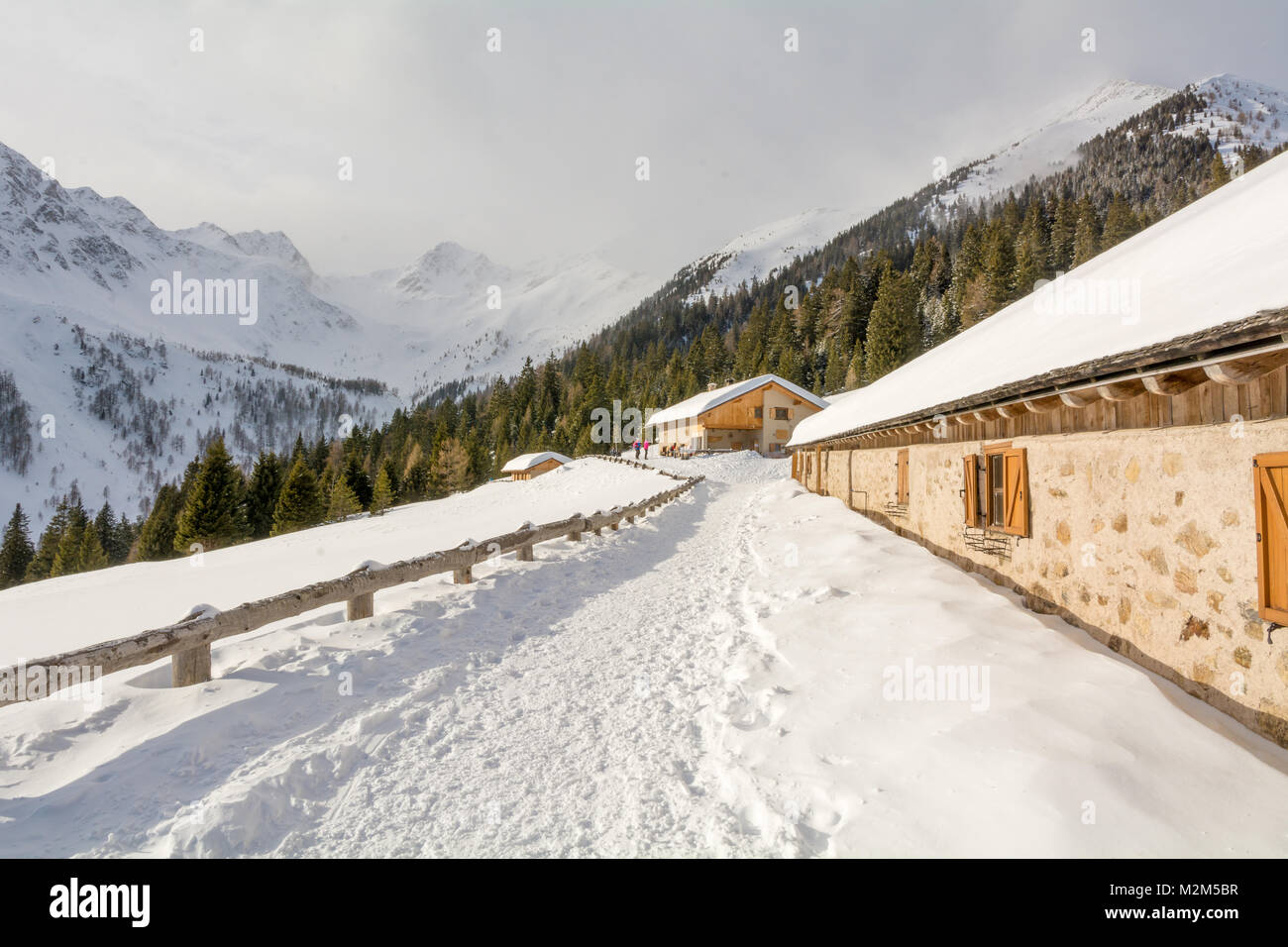 Vista panoramica di idilliaci winter wonderland con cime e tradizionali chalet di montagna nelle Dolomiti nella luce del tramonto Foto Stock