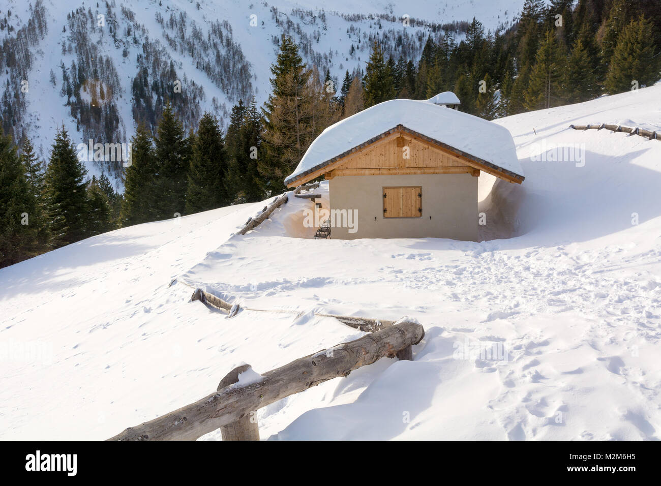 Vista panoramica di idilliaci winter wonderland con cime e tradizionali chalet di montagna nelle Dolomiti nella luce del tramonto Foto Stock