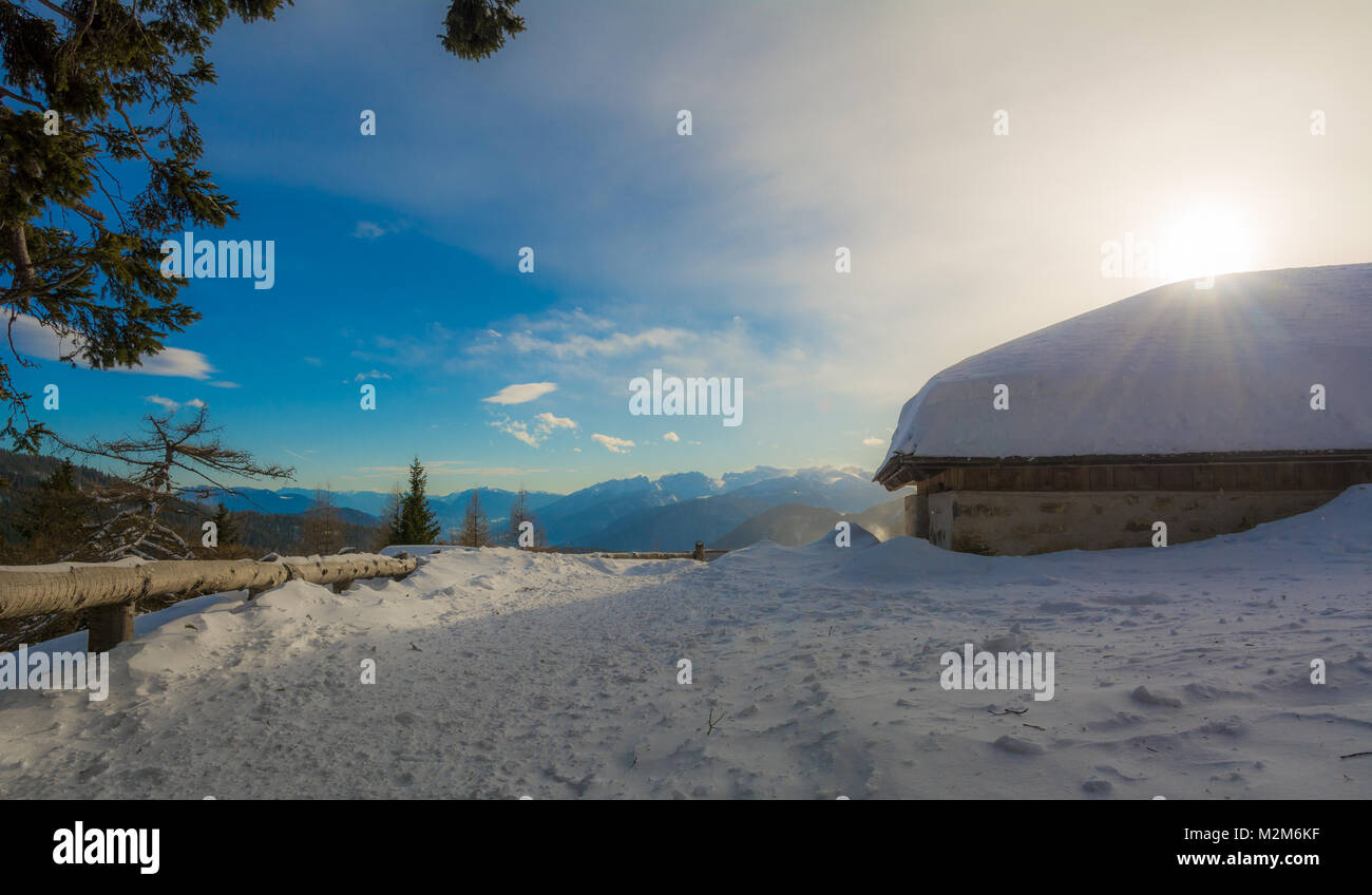 Vista panoramica di idilliaci winter wonderland con cime e tradizionali chalet di montagna nelle Dolomiti nella luce del tramonto Foto Stock