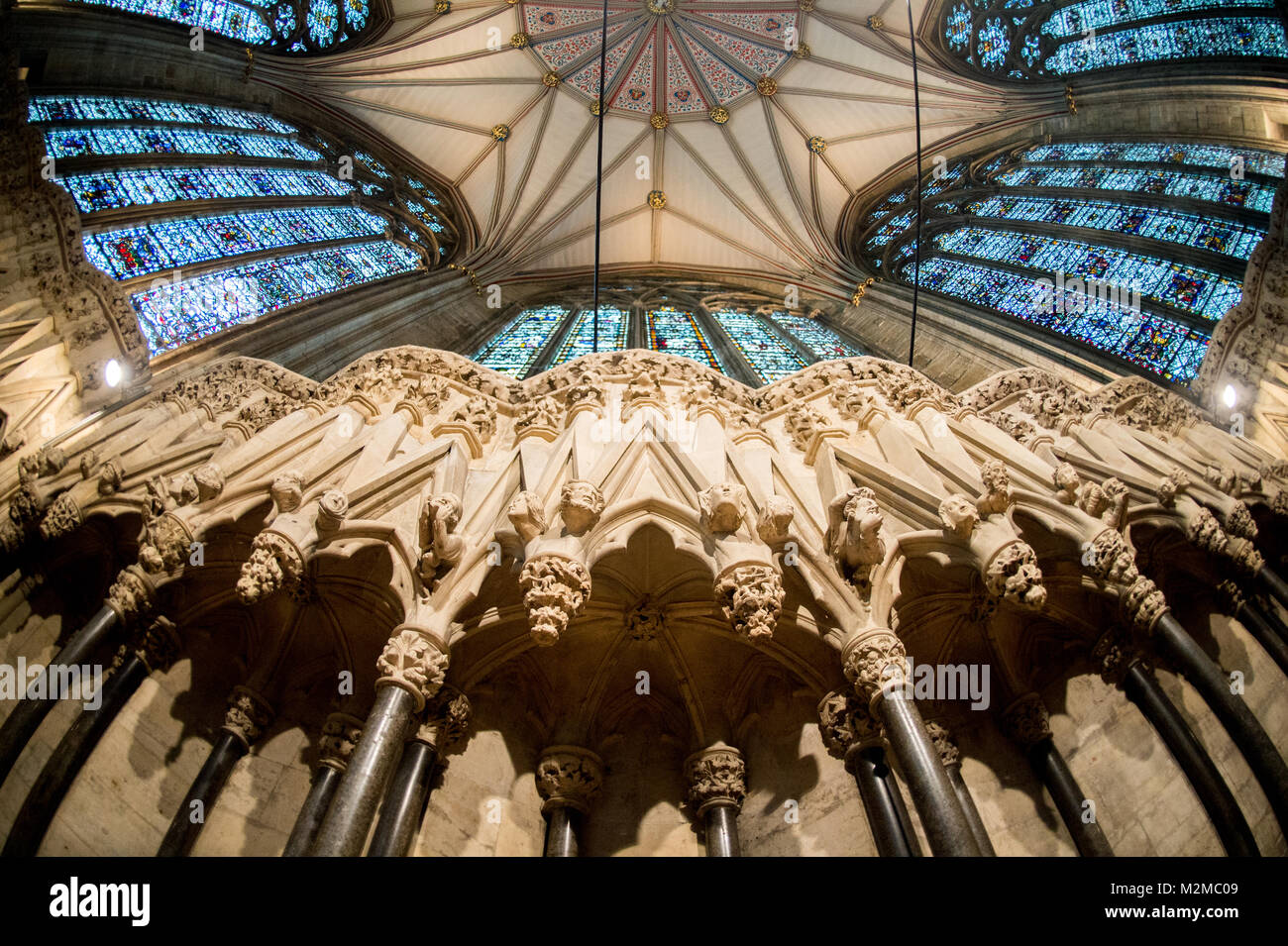 Vista dal di sotto di statue di volti umani e macchiare le finestre di vetro della casa del Capitolo nella cattedrale di York Minster e York, nello Yorkshire, Regno Unito Foto Stock
