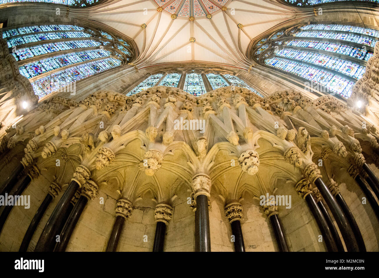 Vista dal di sotto di statue di volti umani e macchiare le finestre di vetro della casa del Capitolo nella cattedrale di York Minster e York, nello Yorkshire, Regno Unito Foto Stock