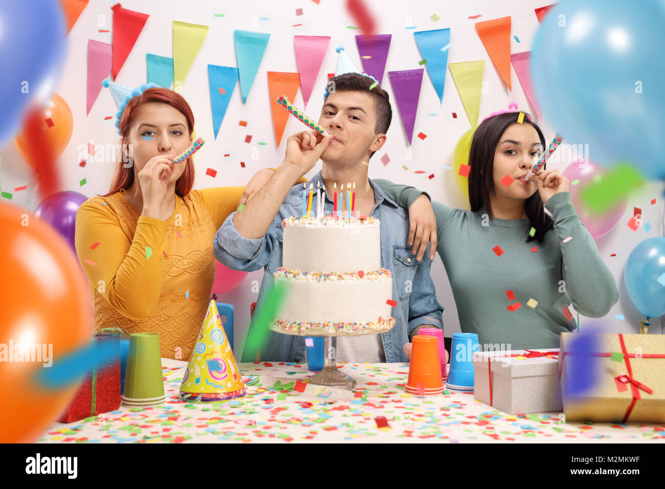Gli adolescenti con party di corna e una torta per festeggiare un compleanno Foto Stock